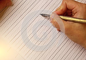 Female hand writes with the inky pen on empty white paper sheet with stripes. stationery on desk close up top view. spelling