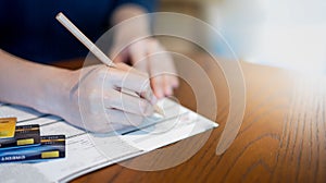 The female hand writing on the Blank credit application form  for appling the credit card on table wood