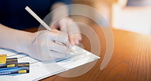 The female hand writing on the Blank credit application form  for appling the credit card on table wood