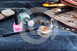 Female handbag with cosmetics and mobile on jeans background