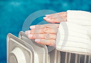 Female hands above the heater