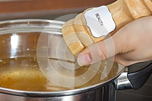 Female hands add to the pot the seasoning