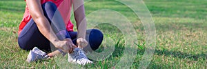 Female hands adjust her running shoes before practice. Runner getting ready for training. Sport active lifestyle concept. Outdoor