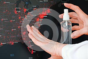 Female hands with antiseptic in front of coronavirus spread USA map