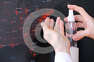 Female hands with antiseptic in front of coronavirus spread USA map