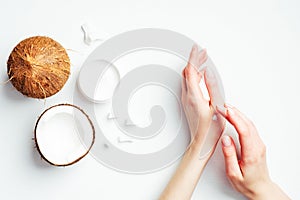 Female hands applying coconut cream on white background. Coconut organic cosmetics, oil, lotion for hand skin care, natural