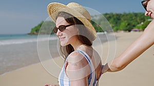 Female hands applying sunscreen on woman's back at tropical beach. Happy girls in bikini put sun cream on skin at