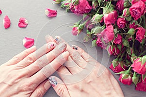 Female hands with art nail manicure and small pink roses