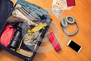 Female hands with Asian money and foreign passport. Suitcase with things on the floor.Travel concept