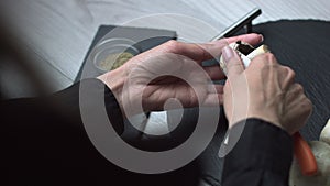 Female hands with a beautiful manicure on the fingers cut mushrooms with a kitchen knife on a black board, close up. Champignon. w