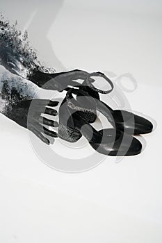 Female hands in black paint reach for new black leather shoes on a white background. top view fashion shoes spring summer 21/22