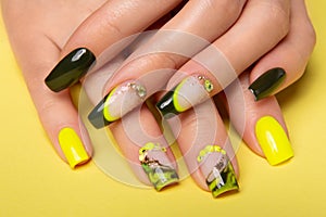 Female hands with black and yellow nail design. Yellow nail polish manicured hands. Female hands on yellow background