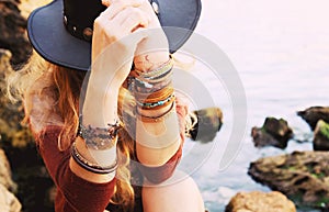 Female hands with boho chic bracelets holding black hat