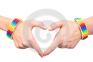 Female hands with a bracelet patterned as the rainbow flag showing heart sign. on white