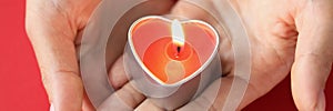 In female hands burning candle in form of heart