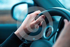 Female hands on car steering wheel. Woman driver traveling along the road through countryside landscape. Road trip concept for