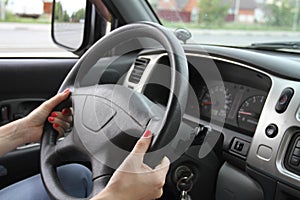 Female hands on a car wheel