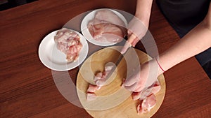 Female hands chef cutting raw chicken meat breast.