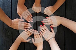 Female hands and child& x27;s hands on a wooden black board as a team, strength and unity of the family, many hands