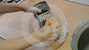 Female hands chopping raw carrots with a trowel. Home kitchen.