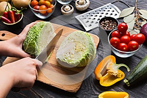 Female hands chopping savoy cabbage on wooden board