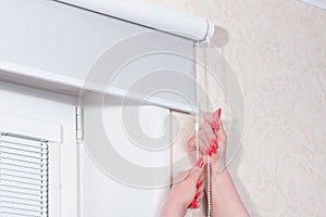 Female hands close rolling shutters at window