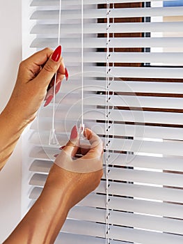 Female hands close rolling shutters at window. Horizontal blinds. Vertical.