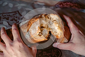 Female hands close-up breaking fresh baguette bread