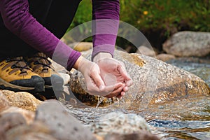 female hands close-up draw water from a mountain stream to quench thirst, drink from a clean source of water. tourist on