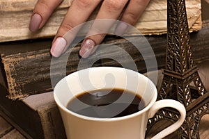 Female hands, coffe cup and an old books