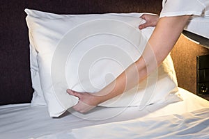 Female hands corrected pillow on the bed