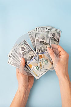 Female hands counting 100 dollar bills isolated on a blue background.