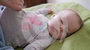 Female Hands Covering a Baby Lying in Bed