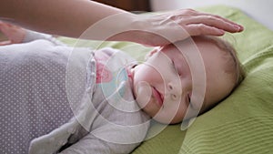 Female Hands Covering a Baby Lying in Bed