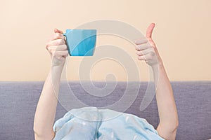 Female hands with a cup of coffee and show a thumbs up sign