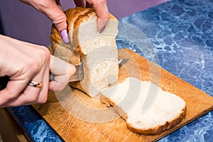 Female hands cut bread on wooden board