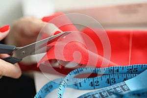 Female hands cut red cloth with scissors