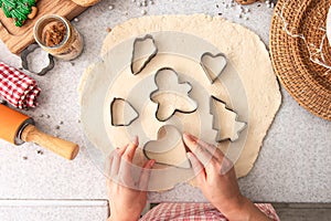 Female hands cut shapes and make Christmas cookies.