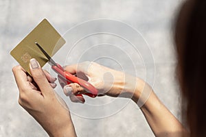 Female hands cutting credit card with scissors.