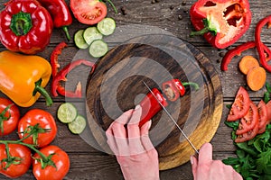 Female hands cutting hot peppers at table, top view