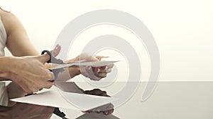 Female hands cutting a sheet of paper with scissors