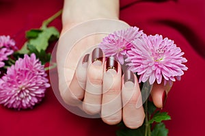 Female hands with dark red nail design.
