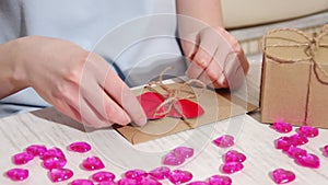 Female hands decorate a brown paper envelope tied with a rope with a red paper heart, full hd, close up