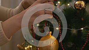 Female hands decorate the Christmas tree with beautiful glass balls