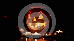 Female Hands Decorate Table with Burning Candles in Background of a Pumpkin Head
