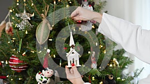 Female hands decorating Christmas tree in Slow Motion. Preparing for winter holidays