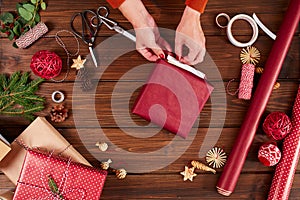 Female hands decorating gift red boxes for Christmas Holiday. Hands close up.