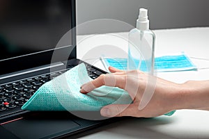 Female hands disinfecting laptop keyboard using Disinfectant spray, Alcohol sanitizer, wet disinfectant wipes. Woman cleaning