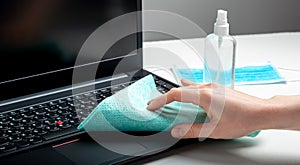 Female hands disinfecting laptop keyboard using Disinfectant spray, Alcohol sanitizer, wet disinfectant wipes. Woman cleaning