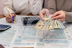 Female hands with dollar and 1040 tax form